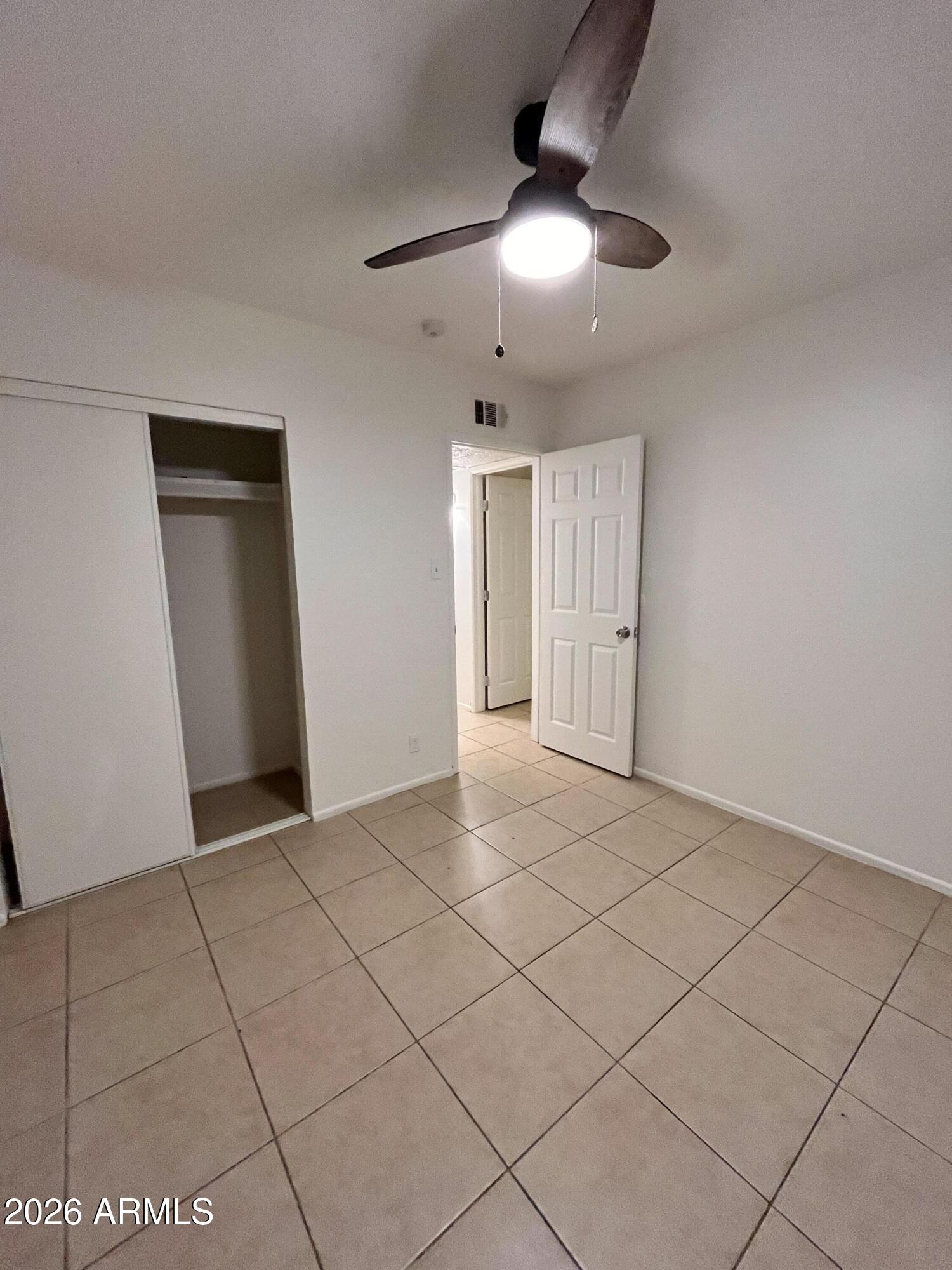 1224 South Smith Road Tempe, AZ 85281 - Photo 11 of 19 an empty room with chandelier fan and kitchen view