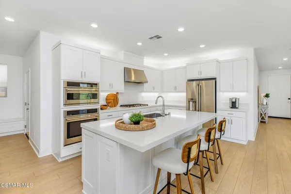a kitchen with a stove a refrigerator and a dining table with wooden floor