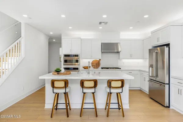 a kitchen with refrigerator and chairs