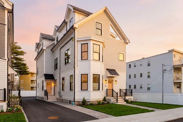 a view of a white building among the street with parked cars