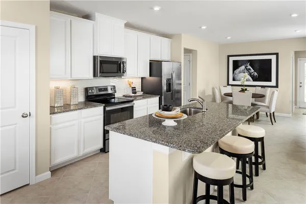 a kitchen with stainless steel appliances granite countertop a stove a microwave a sink a dining table and chairs