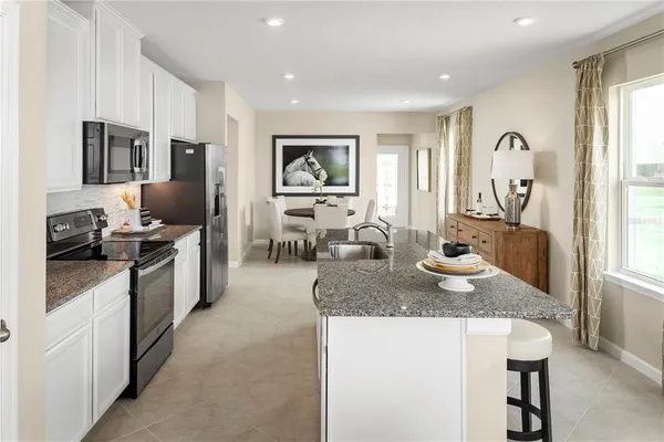 a kitchen with stainless steel appliances granite countertop a stove top oven a sink a dining table and chairs