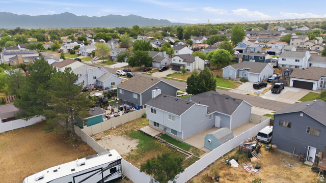 7910 Woolley Way Magna, UT 84044 - Photo 23 of 26 Light blue two-story residence with a dark shingle roof and a spacious backyard
