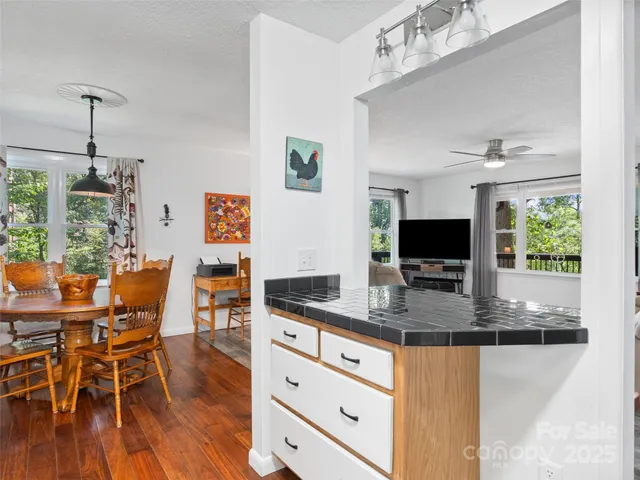 a kitchen with stainless steel appliances granite countertop a stove top oven a dining table and chairs with wooden floor