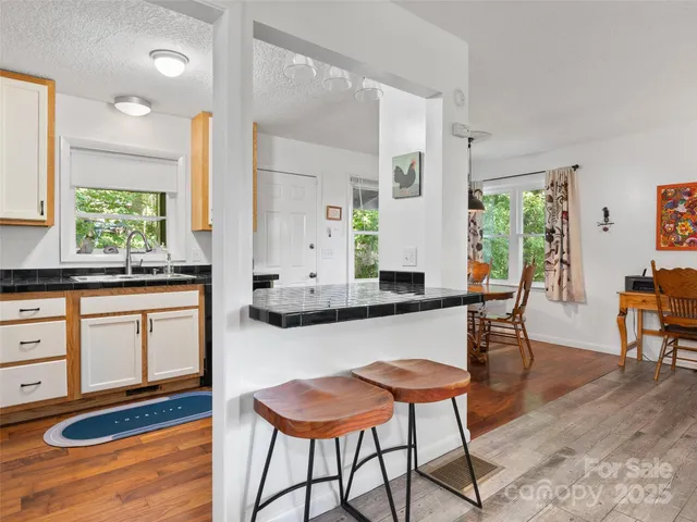 a kitchen with stainless steel appliances kitchen island granite countertop a table chairs sink and cabinets