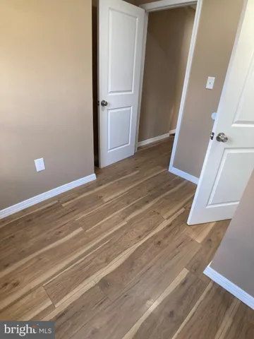 a view of an empty room with wooden floor and window