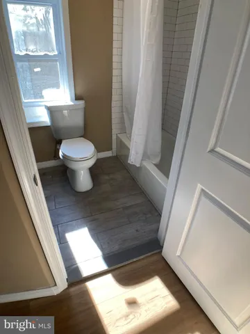 a view of an empty room with wooden floor and closet