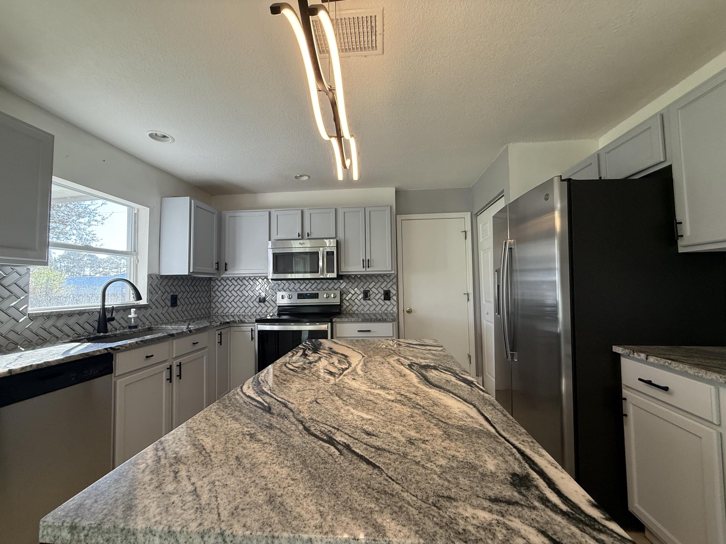 1925 Southwest Libra Lane Port St. Lucie, FL 34984 - Photo 16 of 49 a kitchen with kitchen island a sink appliances and cabinets