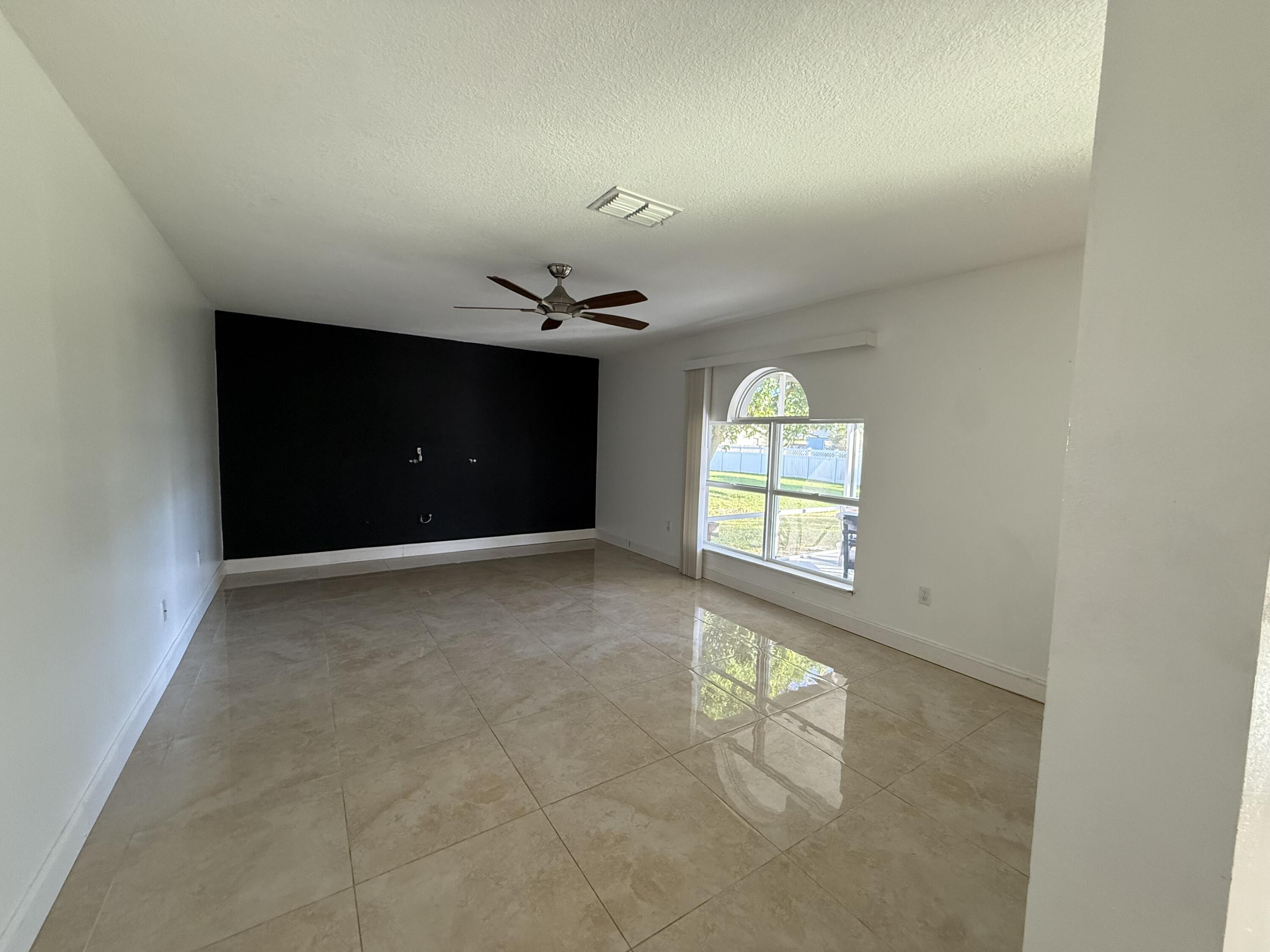 1925 Southwest Libra Lane Port St. Lucie, FL 34984 - Photo 17 of 49 an empty room with windows and chandelier fan