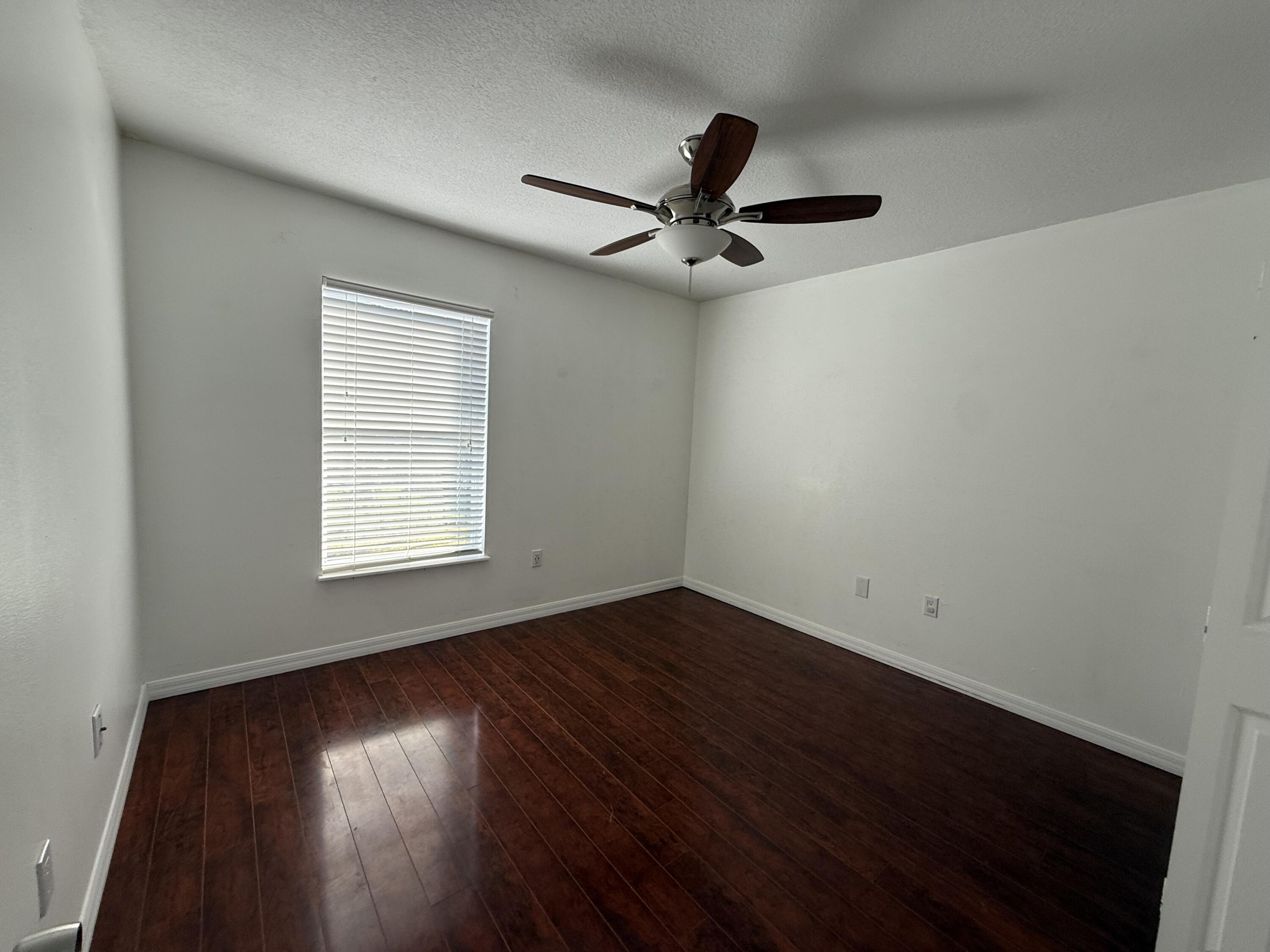 1925 Southwest Libra Lane Port St. Lucie, FL 34984 - Photo 32 of 49 an empty room with wooden floor fan and windows