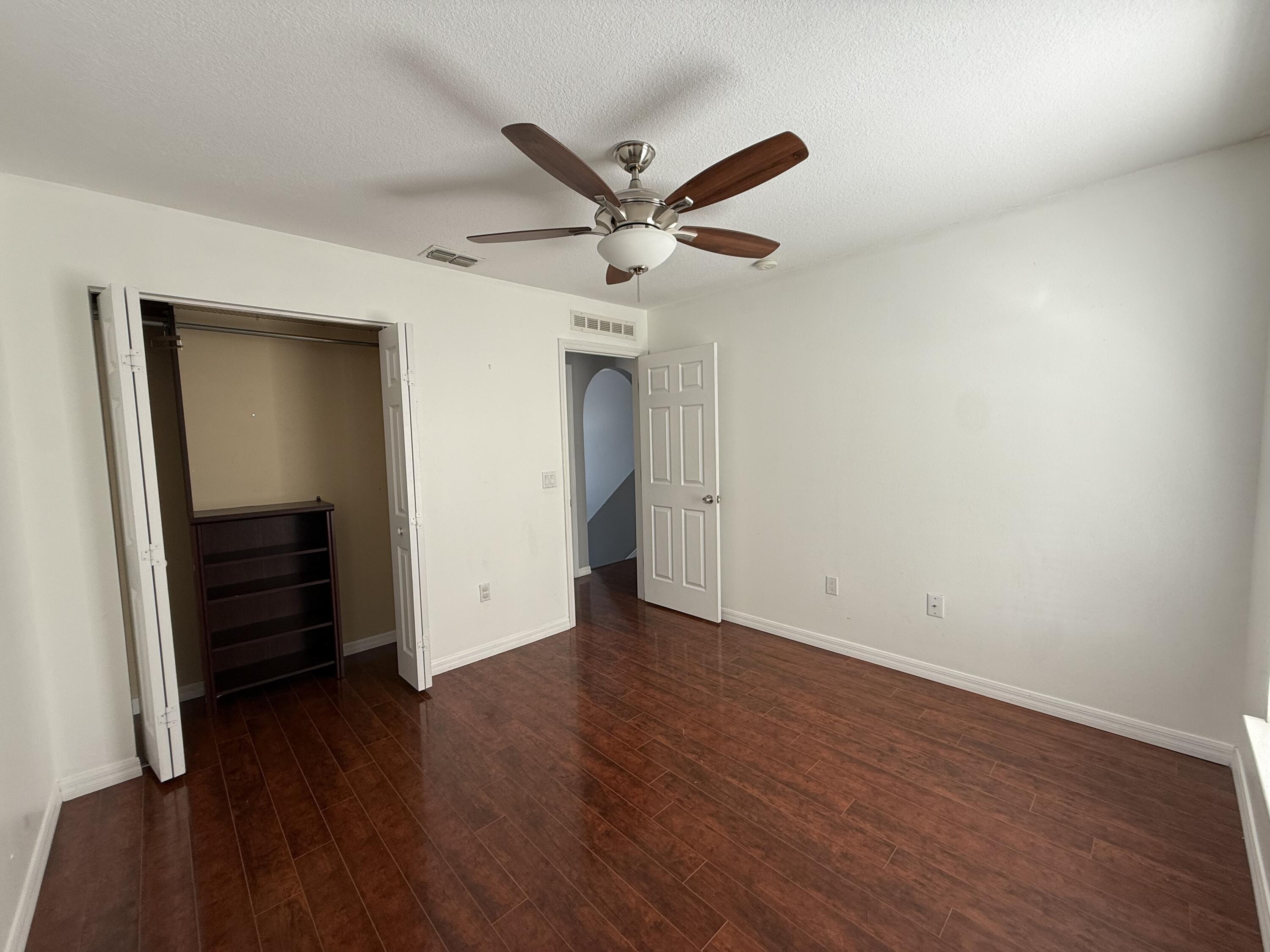 1925 Southwest Libra Lane Port St. Lucie, FL 34984 - Photo 33 of 49 an empty room with wooden floor and a ceiling fan