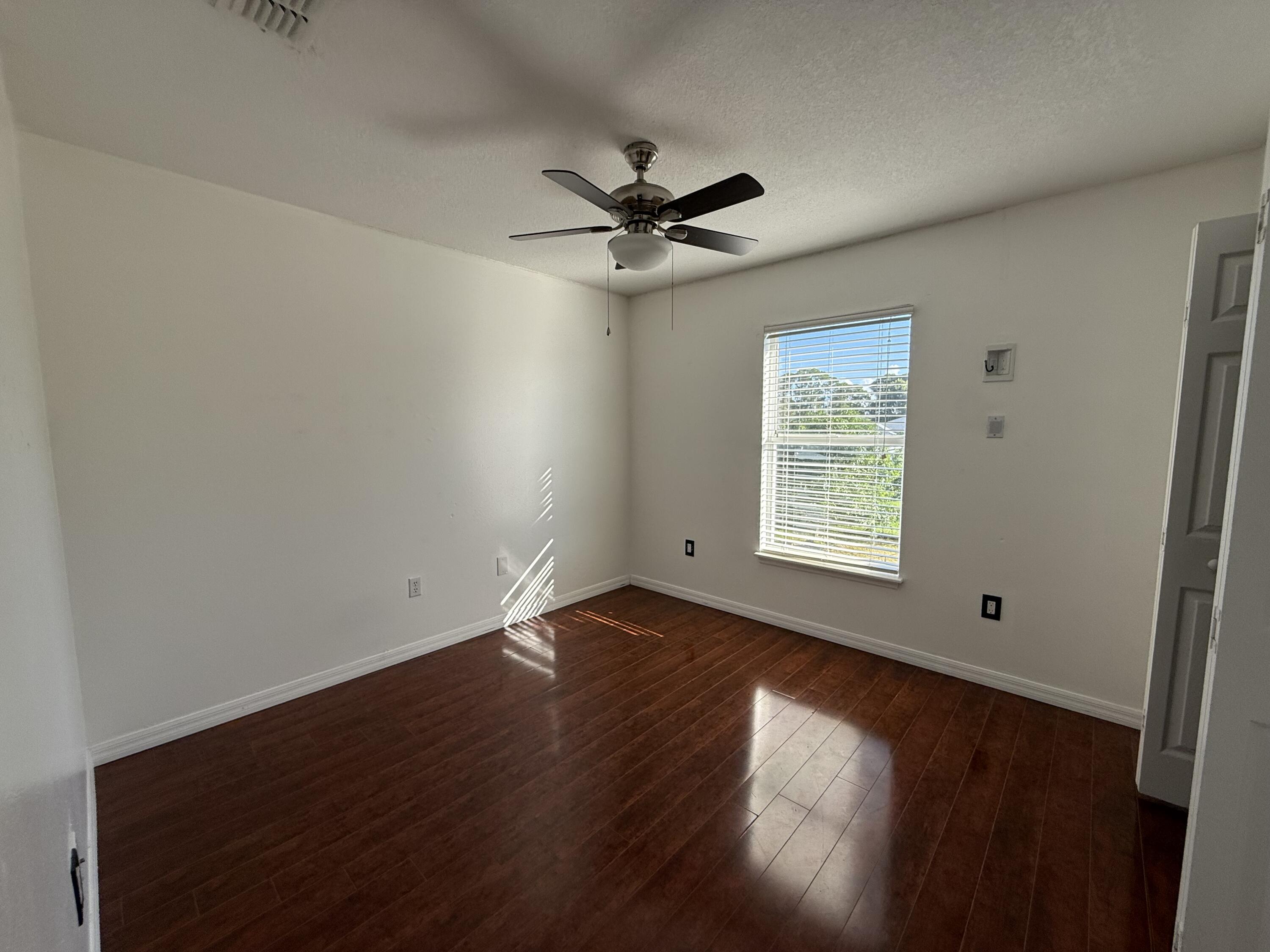 1925 Southwest Libra Lane Port St. Lucie, FL 34984 - Photo 34 of 49 an empty room with wooden floor fan and windows