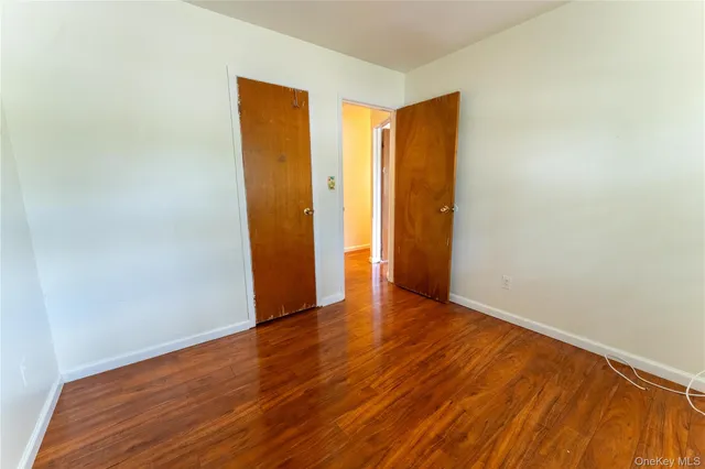 a view of an empty room with wooden floor and closet