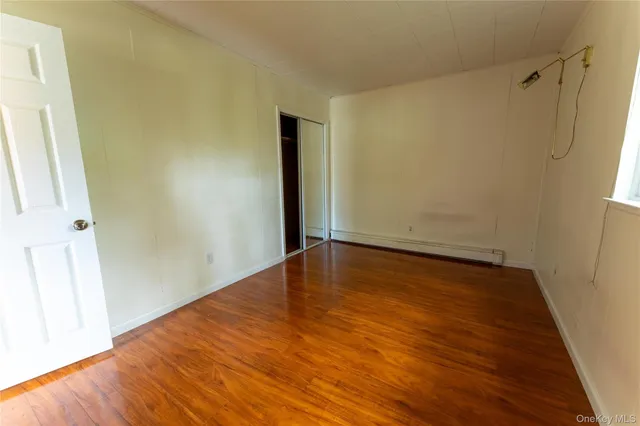 an empty room with wooden floor and entrance