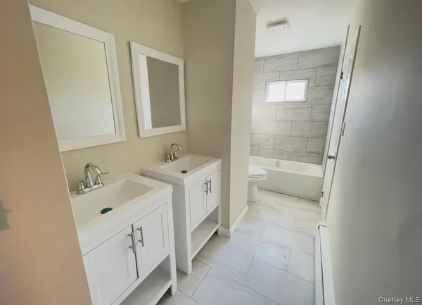 a bathroom with a double vanity sink a mirror and a bathtub