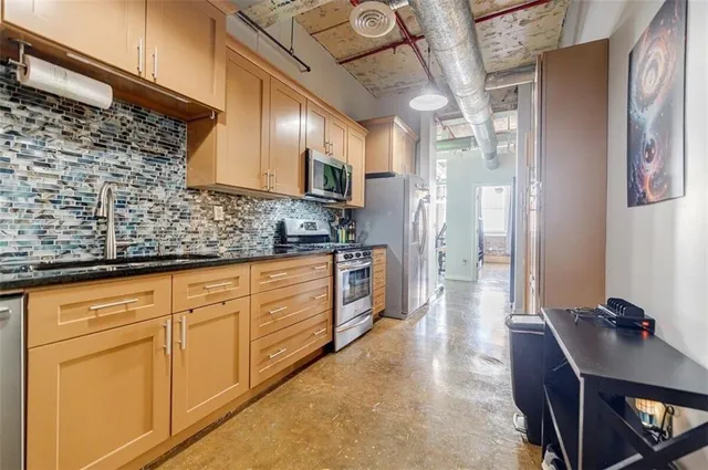 a large kitchen with stainless steel appliances kitchen island granite countertop a refrigerator and a stove top oven