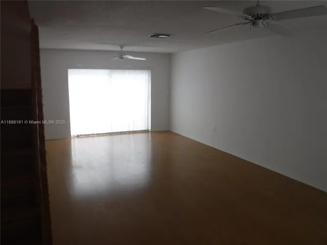 an empty room with windows and refrigerator