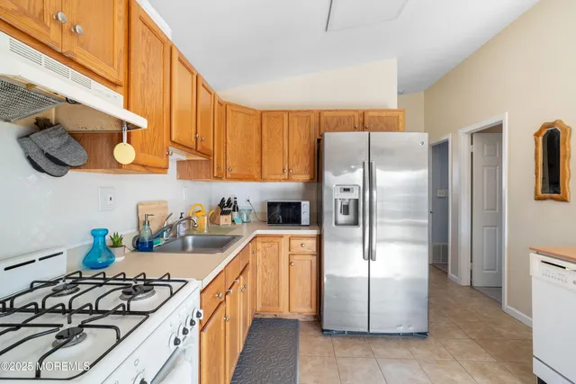 a kitchen with stainless steel appliances granite countertop a refrigerator a stove and a sink