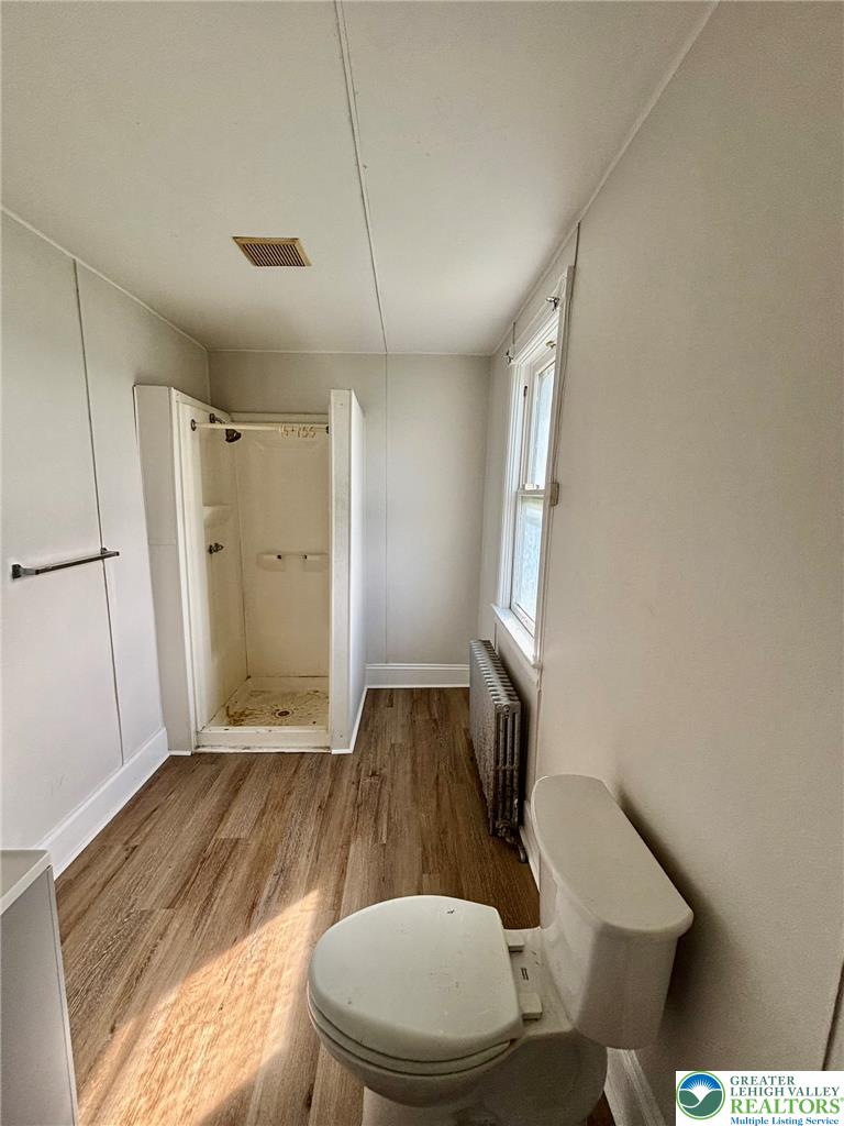 4067 Newburg Road Bethlehem, PA 18020 - Photo 18 of 19 Rich wood-look flooring and a classic radiator anchor this functional, light-filled bathroom space.