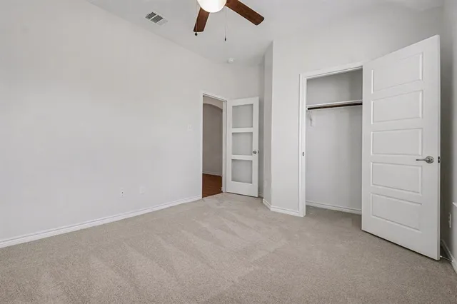 an empty room with closet and a ceiling fan
