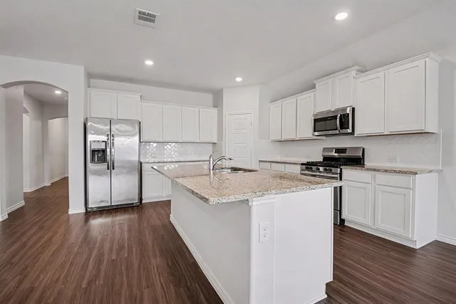 a kitchen with stainless steel appliances granite countertop a sink stove microwave and refrigerator