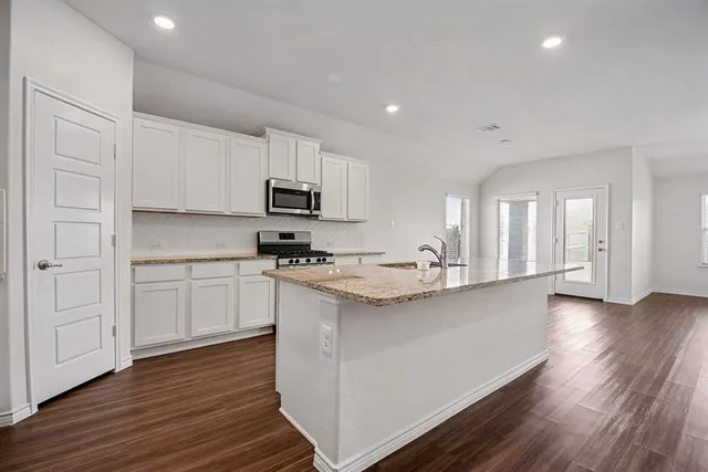 a kitchen with granite countertop a sink cabinets and wooden floor