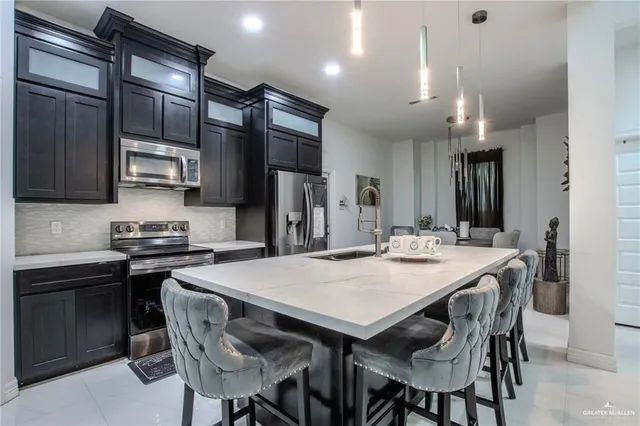 a kitchen with stainless steel appliances granite countertop a stove a refrigerator a sink a dining table and chairs with wooden floor