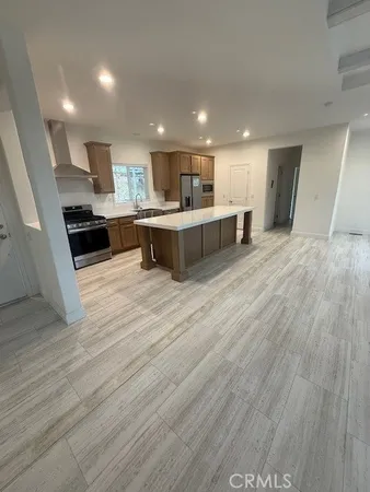 a large white kitchen with kitchen island a sink wooden floor and a living room