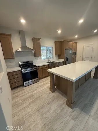 a large white kitchen with wooden floor and stainless steel appliances