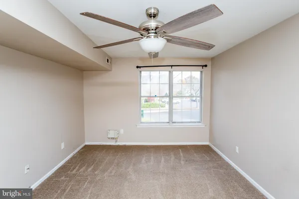 an empty room with a chandelier fan and windows