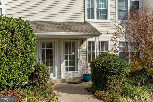 front view of a brick house with a large window and potted plants