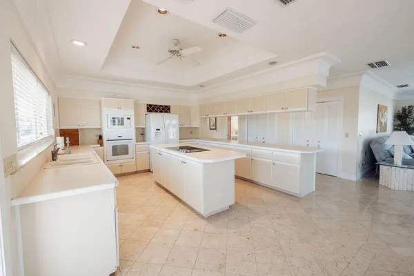 a large white kitchen with a stove a sink dishwasher and a refrigerator with white cabinets