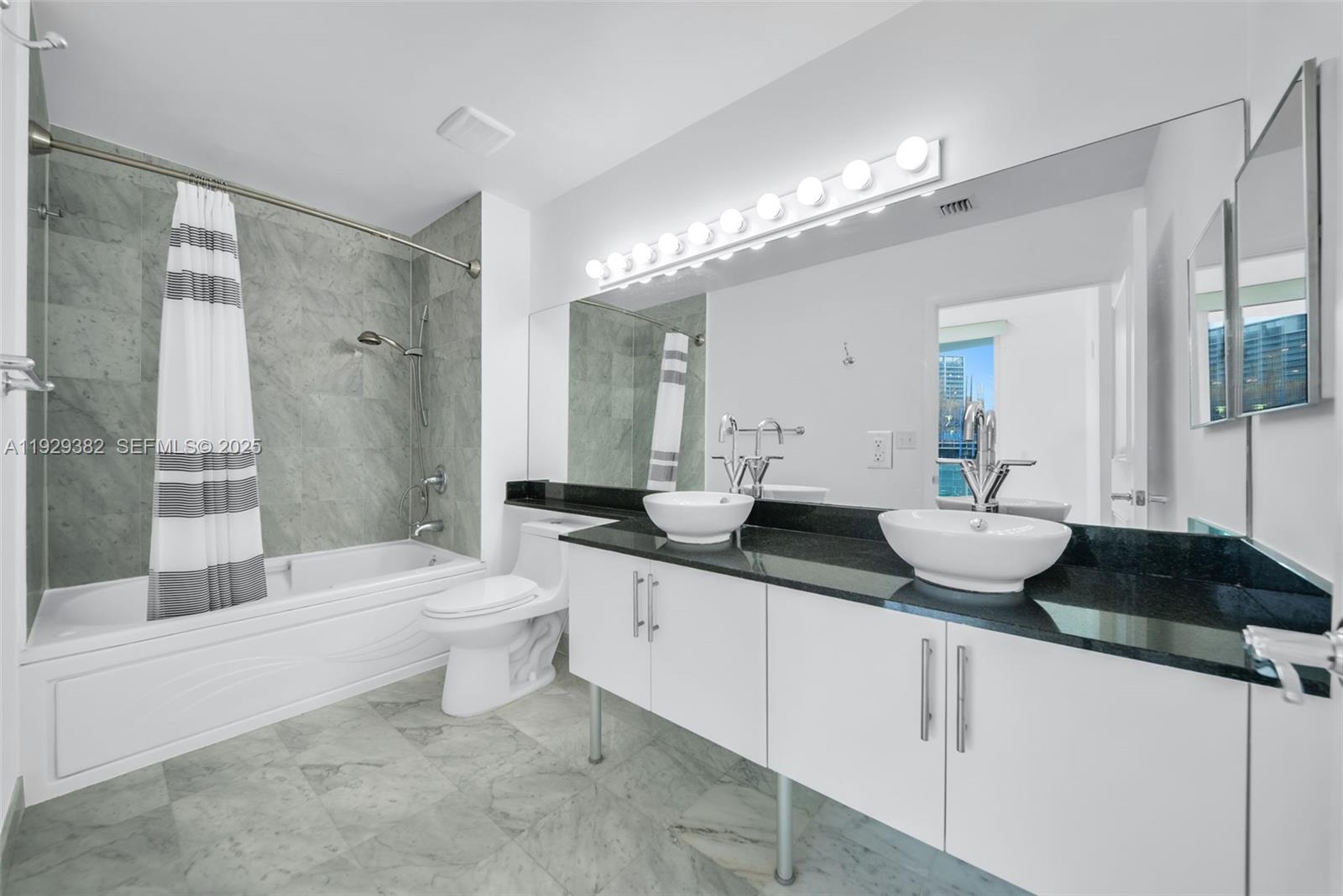 31 Southeast 5th Street, Unit 4314 Miami, FL 33131 - Photo 17 of 40 a bathroom with a double vanity sink a toilet a mirror and bathtub