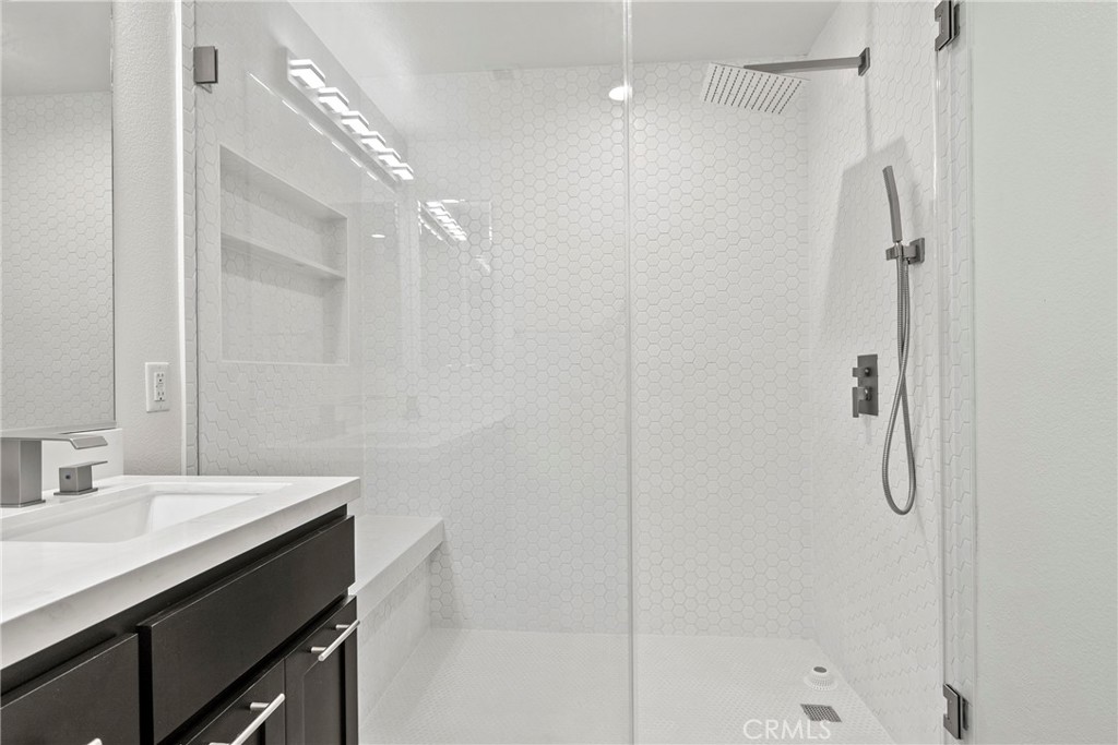 21301 Erwin Street, Unit 206 Woodland Hills, CA 91367 - Photo 12 of 34 a bathroom with a shower sink vanity and a mirror