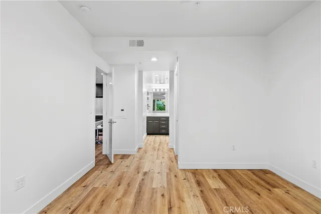 a view of a hallway with wooden floor and a bathroom