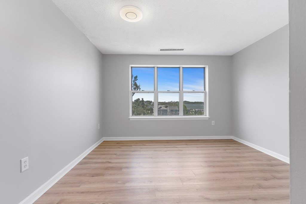 20 Rockland House Road, Unit 402 Hull, MA 02045 - Photo 11 of 40 a view of an empty room with wooden floor and a window