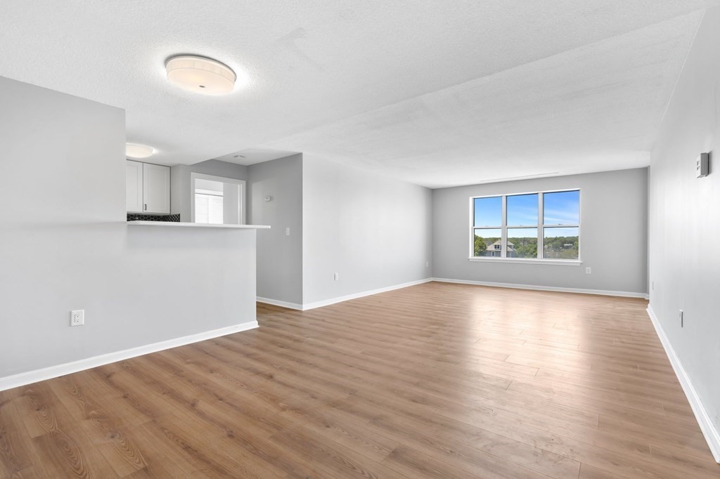 20 Rockland House Road, Unit 402 Hull, MA 02045 - Photo 4 of 40 an empty room with wooden floor cabinet and windows