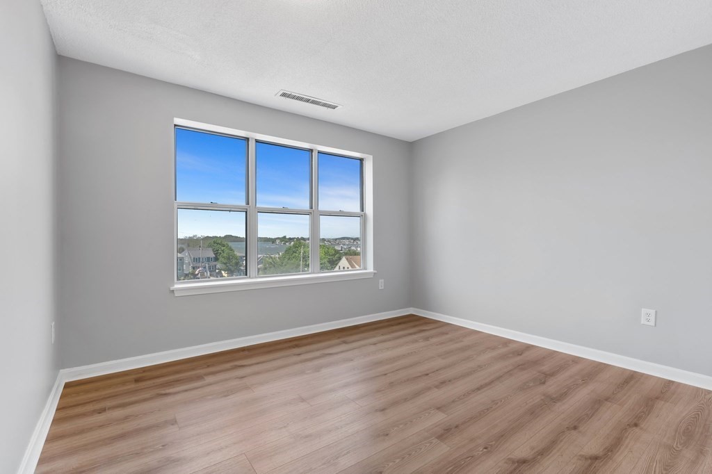 20 Rockland House Road, Unit 402 Hull, MA 02045 - Photo 10 of 40 a view of an empty room with wooden floor and a window