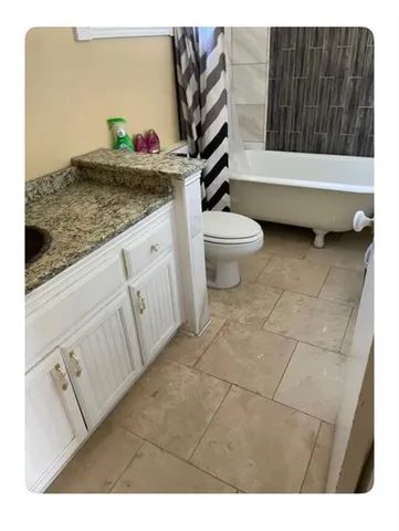 a bathroom with a granite countertop sink a mirror and bathtub