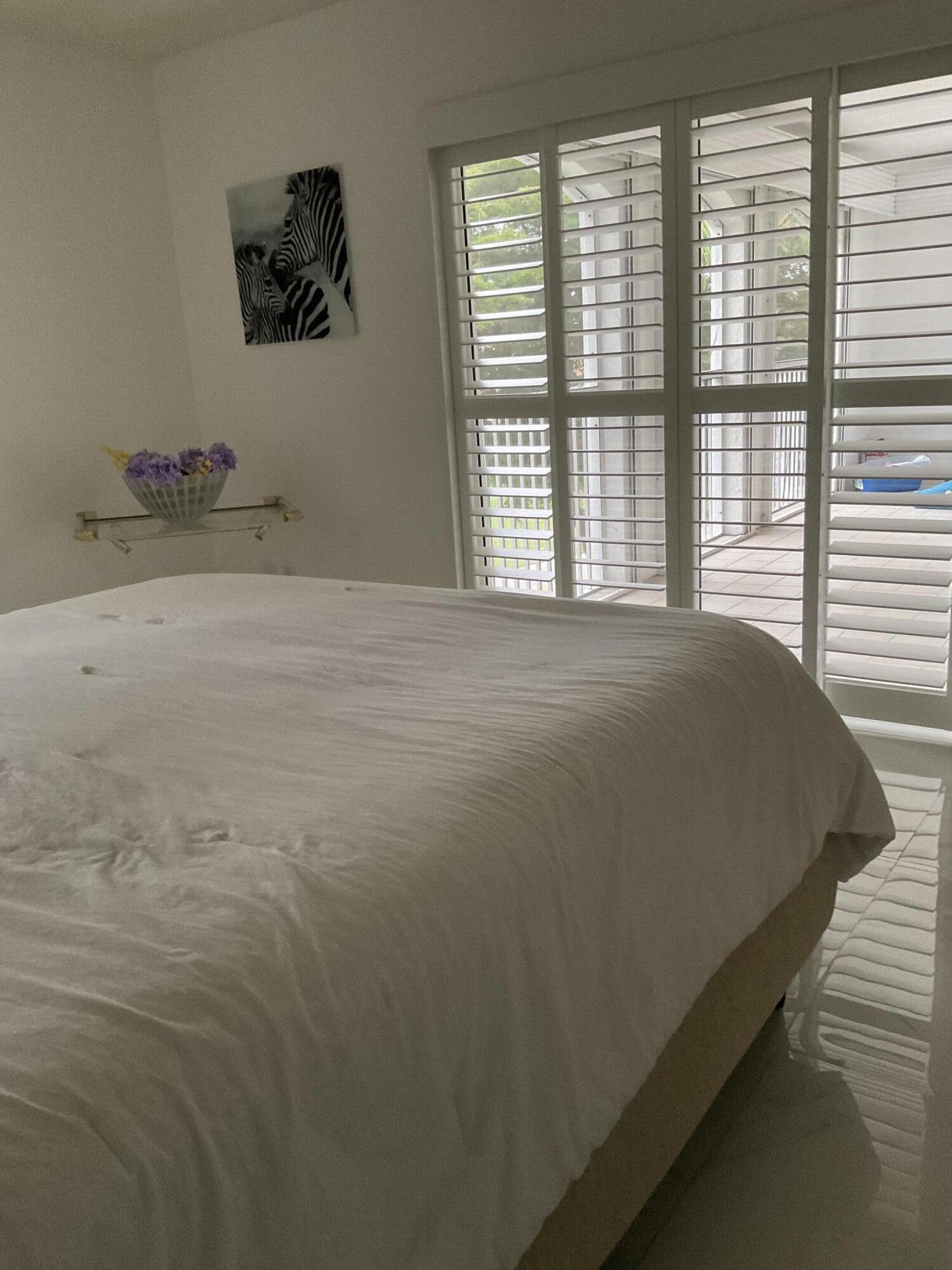 7370 Orangewood Lane, Unit 303 Boca Raton, FL 33433 - Photo 32 of 45 a bed sitting in a bedroom next to a window
