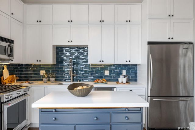 a kitchen with stainless steel appliances white cabinets and a refrigerator