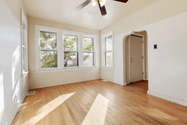 a view of an empty room with window and wooden floor