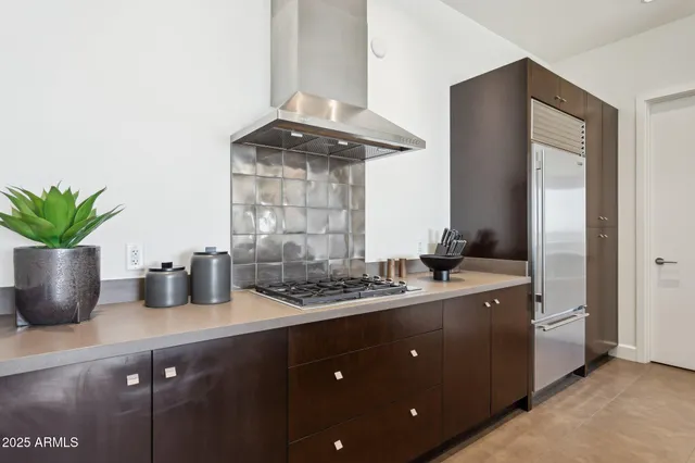 a kitchen with stainless steel appliances kitchen island granite countertop a refrigerator a stove and a sink with wooden floor