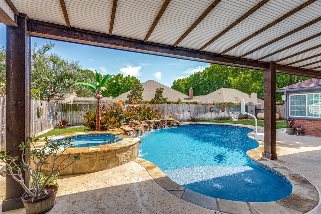 1228 Concho Drive Benbrook, TX 76126 - Photo 31 of 39 Covered patio with exposed wood beams and corrugated roof, overlooking a freeform pool with integrated spa