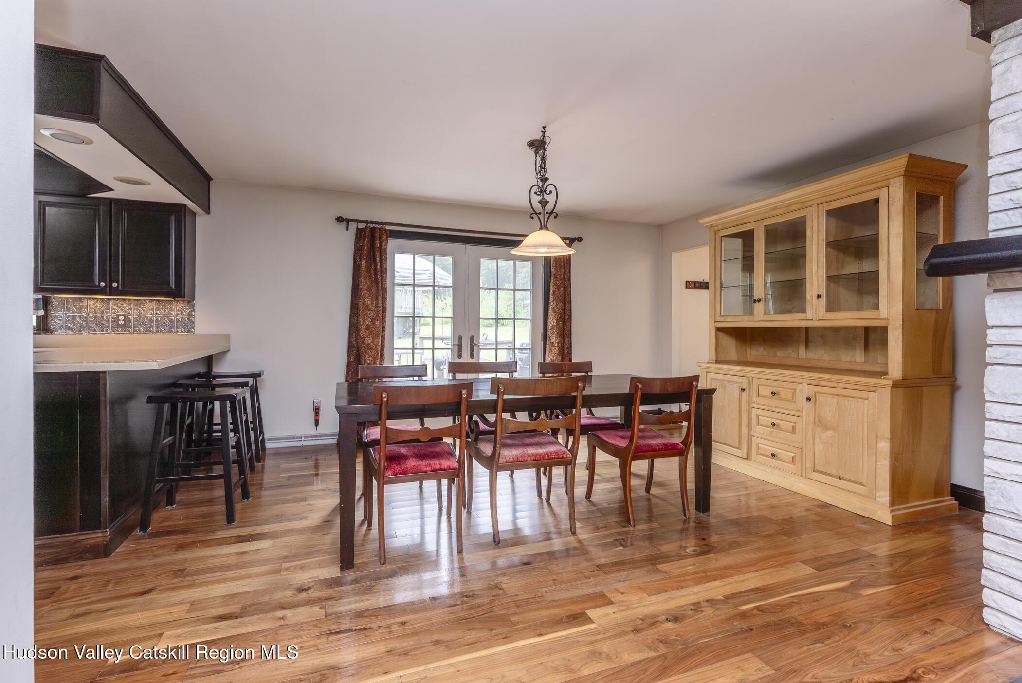 137 Bush Road Stone Ridge, NY 12484 - Photo 11 of 39 a dining room with wooden floor a chandelier a wooden table and chairs
