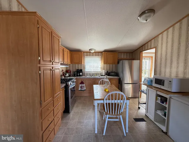 a kitchen with refrigerator a microwave a dining table and chairs