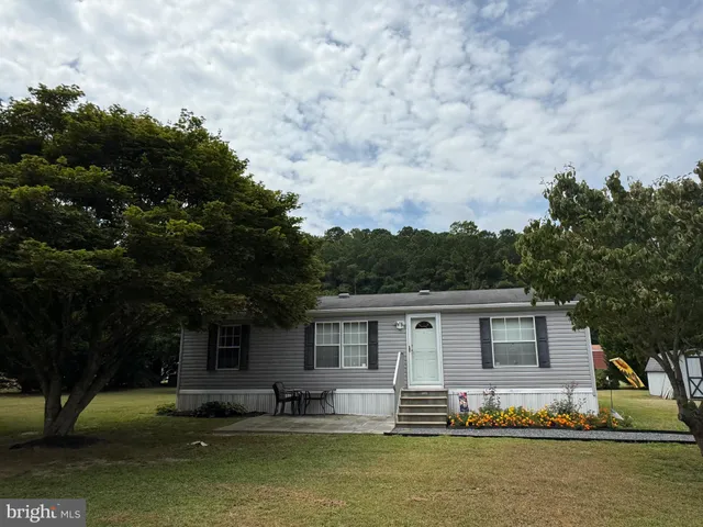 a front view of a house with a garden and trees