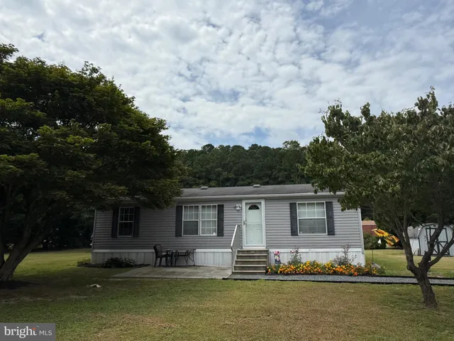 a front view of a house with a garden and trees
