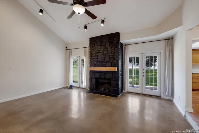 an empty room with windows fireplace and fan