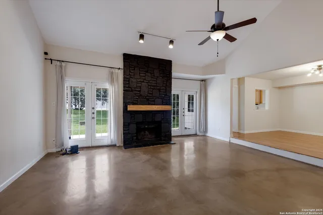an empty room with windows fireplace and a ceiling fan